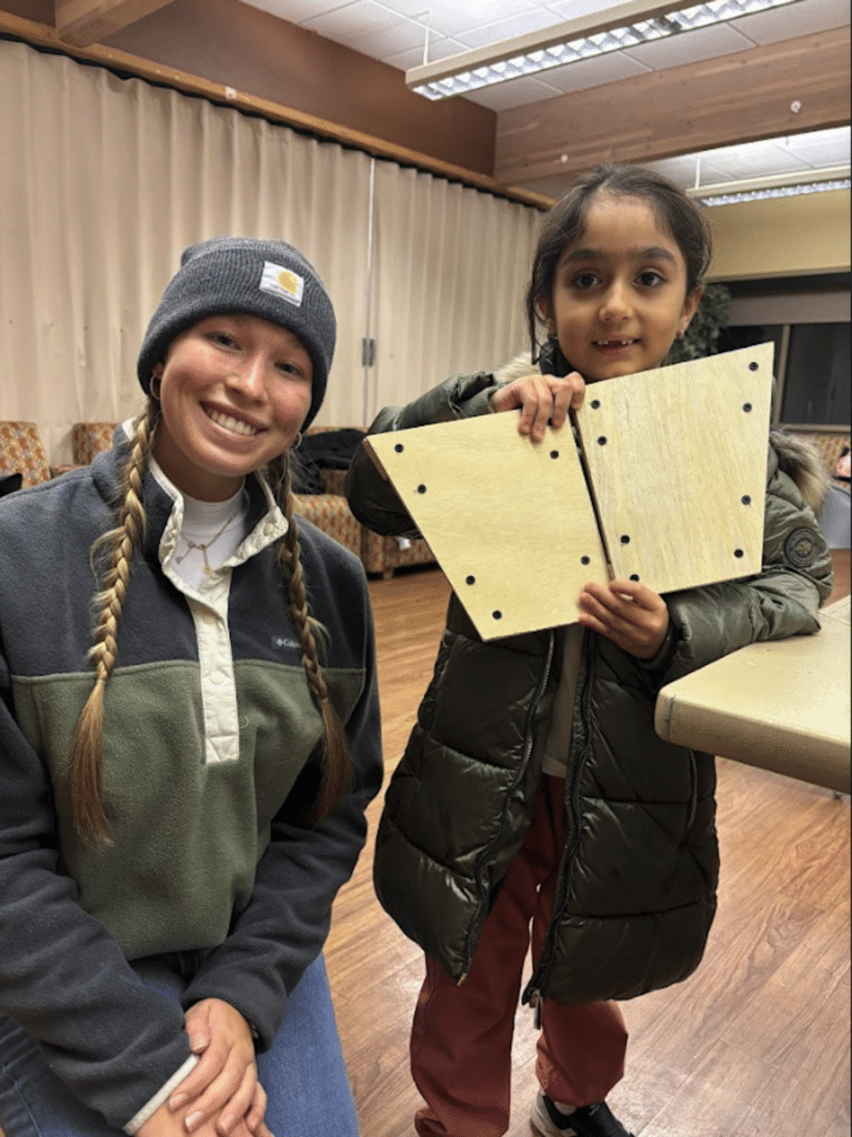 Two young professionals working together at a desk with multiple laptops and a tablet